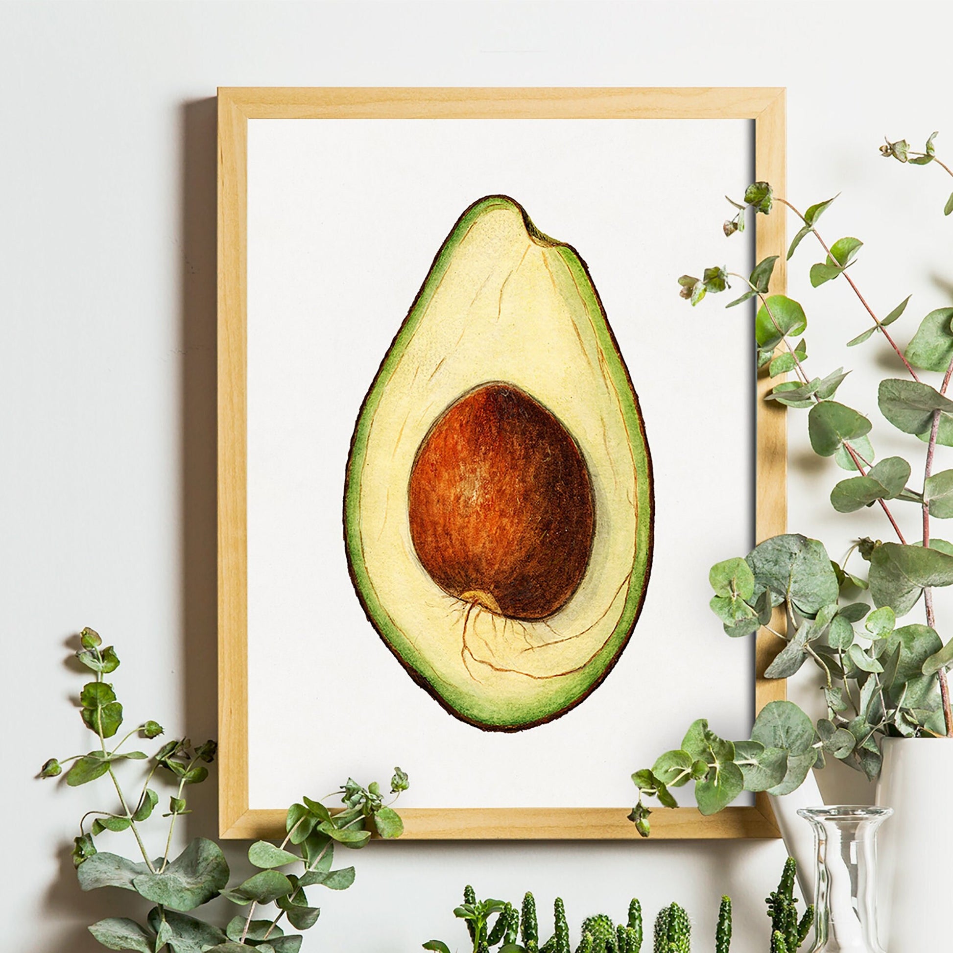 Ingelijste avocado poster aan een lichte muur, omringd door eucalyptus takjes in vaasjes.