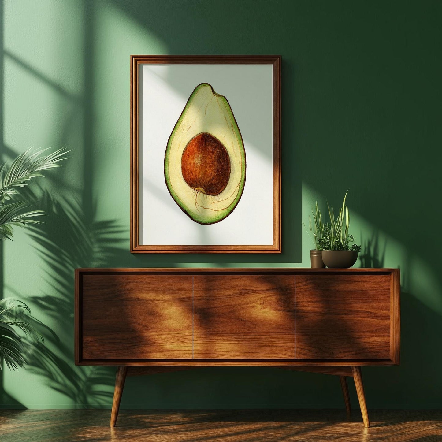 Avocado poster tegen een groene muur waar zonnestralen op schijnen. Eronder staat een jaren 50 kastje met plantjes erop.