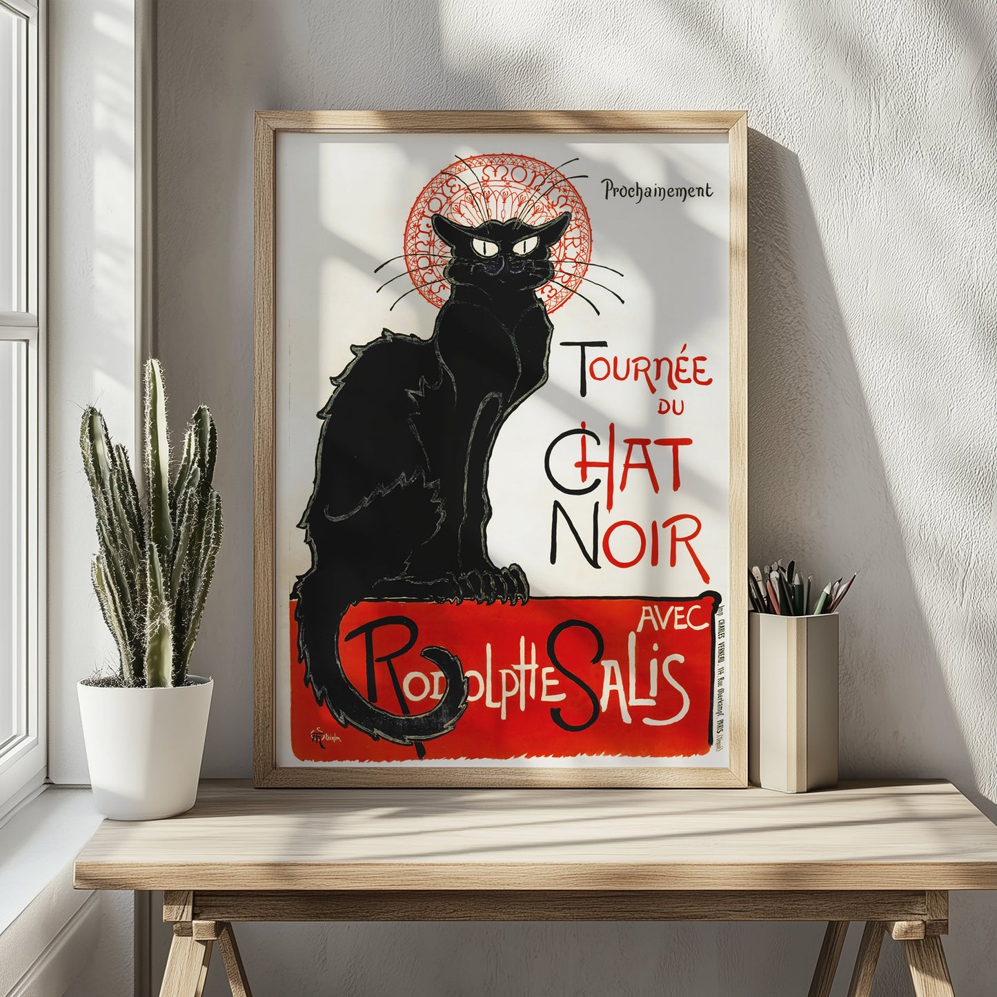 Ingelijste zwarte kat poster op houten tafeltje met links een cactus. warme, natuurlijke sfeer.