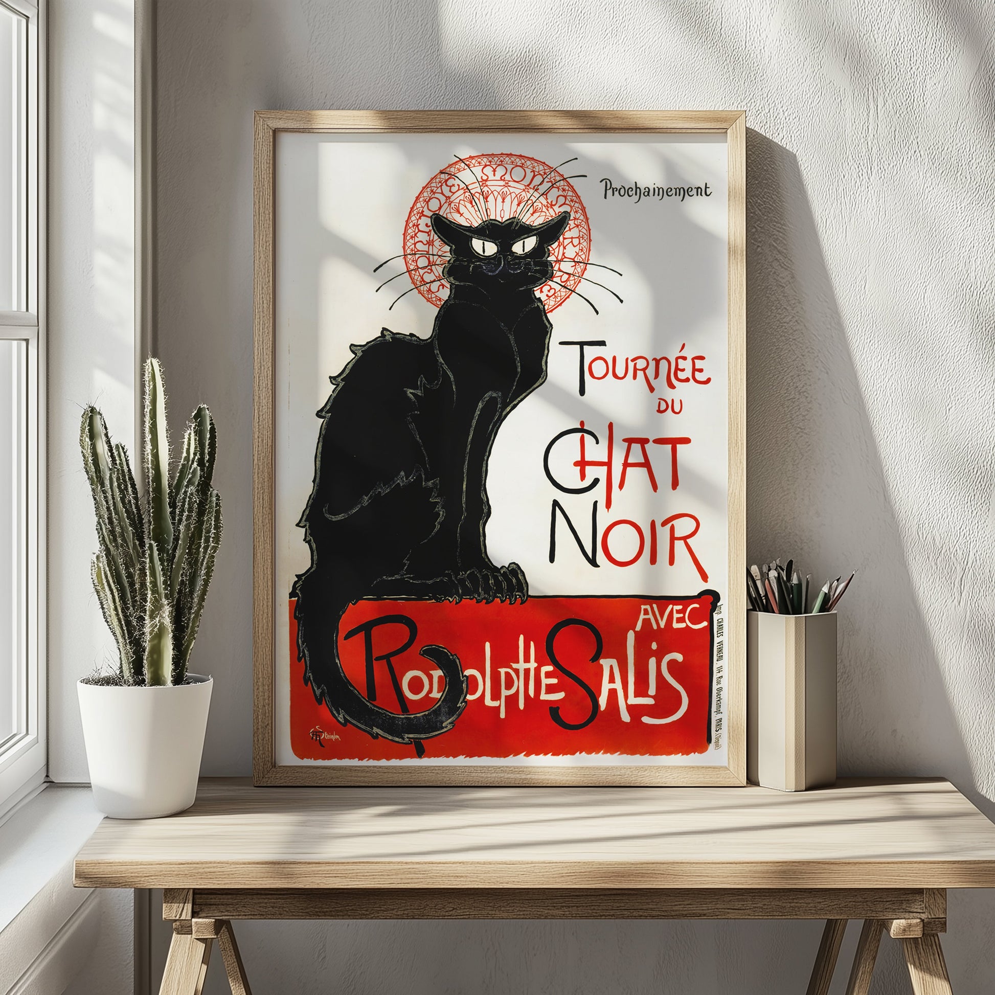 Ingelijste zwarte kat poster op houten tafeltje met links een cactus. warme, natuurlijke sfeer.
